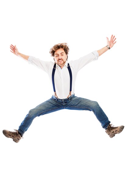 A smiling pretty redhead man with a beard in jeans and a white shirt is jumping. Isolated over white wall. Vertical.