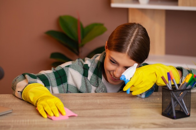 Smiling pretty woman cleans the office at her home