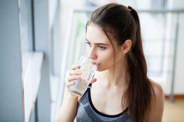 Smiling pretty woman holds a glass of water leaning