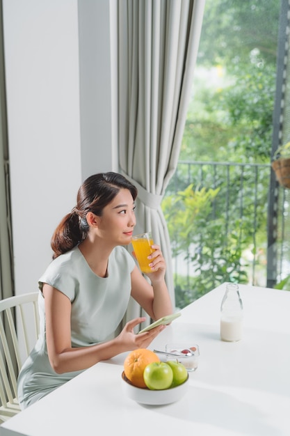 Smiling pretty woman looking at mobile phone and holding glass