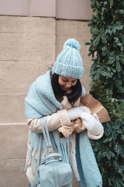 Foto donna graziosa sorridente che cammina all'aperto che tiene il mazzo dell'albero di natale