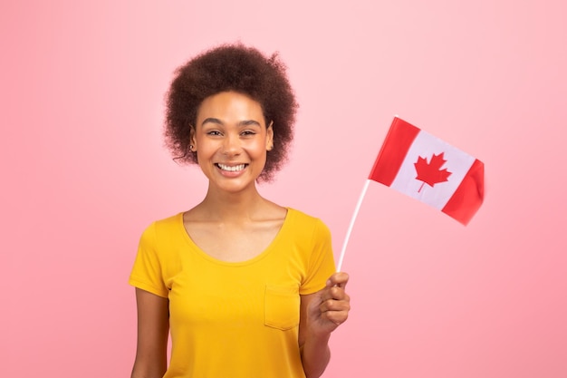 カナダの国旗と黄色の t シャツでかなり若いアフリカ系アメリカ人の巻き毛の女性の笑みを浮かべてください。