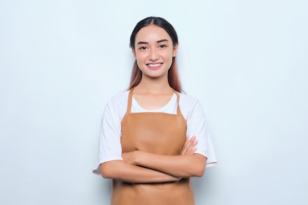 Smiling pretty young barista girl in apron standing with crossed arms feels confident isolated on white background
