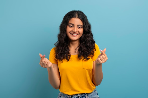 Photo smiling pretty young eastern woman gesturing on blue