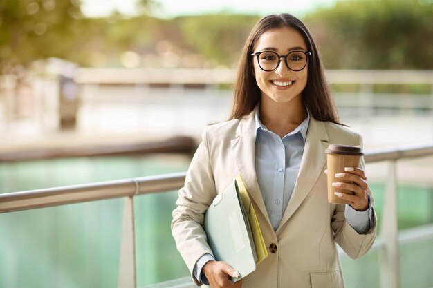 Smiling pretty young european woman in suit glasses with documents enjoy work