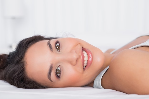 Smiling pretty young woman relaxing in bed