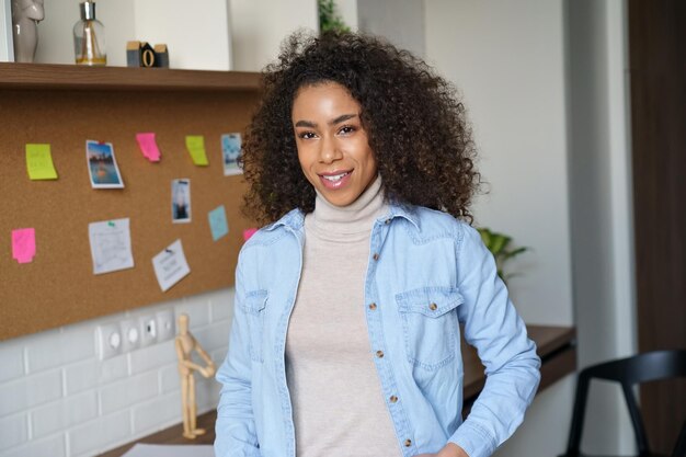 Smiling prettyafricanamerican woman look at camera stand at home office