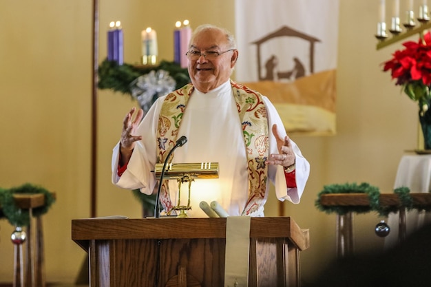 Foto un prete sorridente che pronuncia un discorso in chiesa