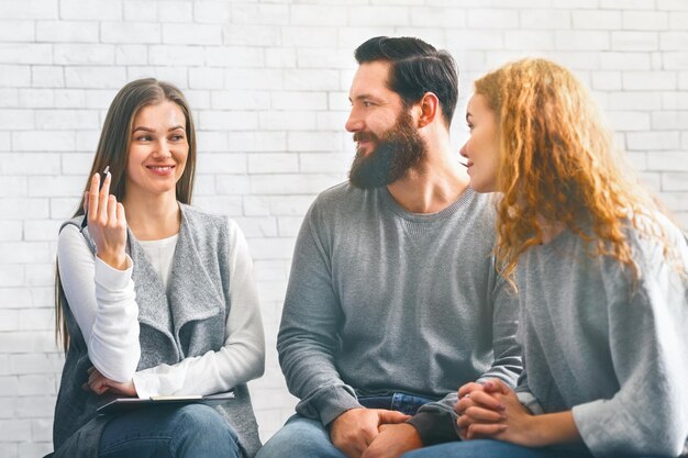 Smiling psychologist talking to group members at therapy session in rehab