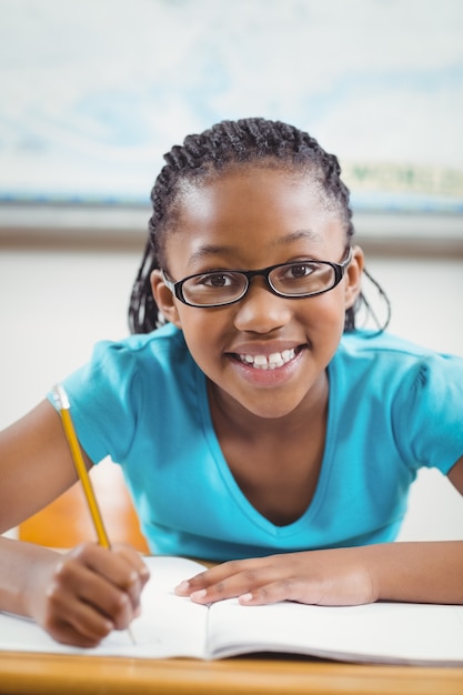 Smiling pupil working at her desk in a classroom