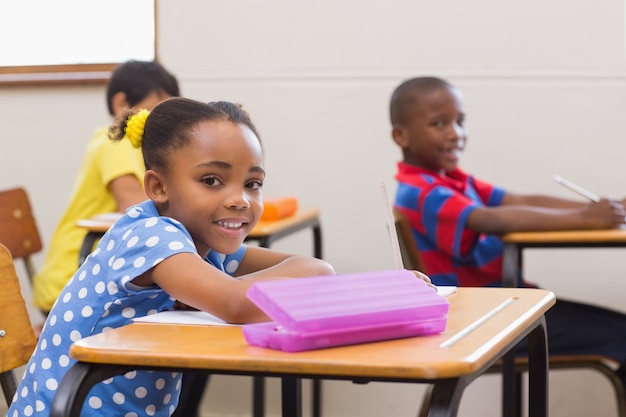 Smiling pupils sitting at her desk 