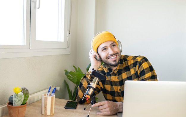 Smiling radio host sitting in office with microphone and headphones