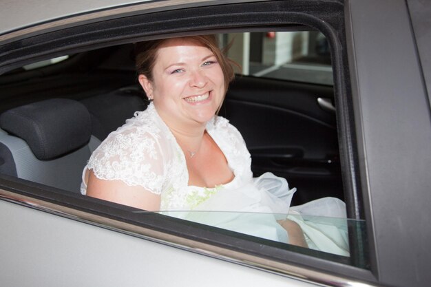 Smiling real bride in grey car