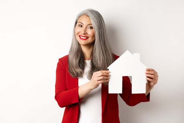 Smiling real estate agent showing paper house clipboard, broker working with client, standing over white background.