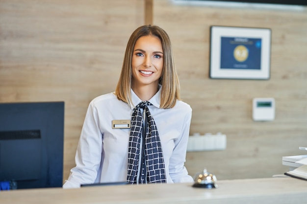 Photo smiling receptionist at hotel front desk