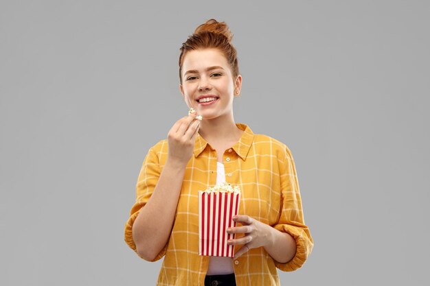 Photo smiling red haired teenage girl eating popcorn