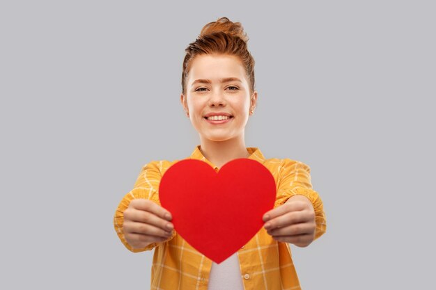 Photo smiling red haired teenage girl with heart