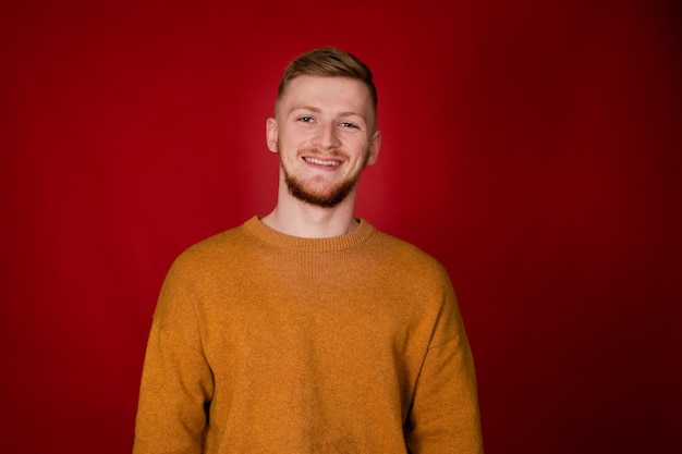 Smiling redbeard guy in mustard sweater looks at front