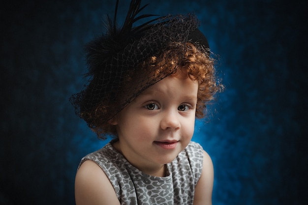 그녀의 머리에 모자와 함께 귀여운 아이 재미 있은 얼굴로 웃는 빨간 머리 소녀