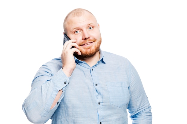 Smiling redhead man with a beard is talking on the phone. 