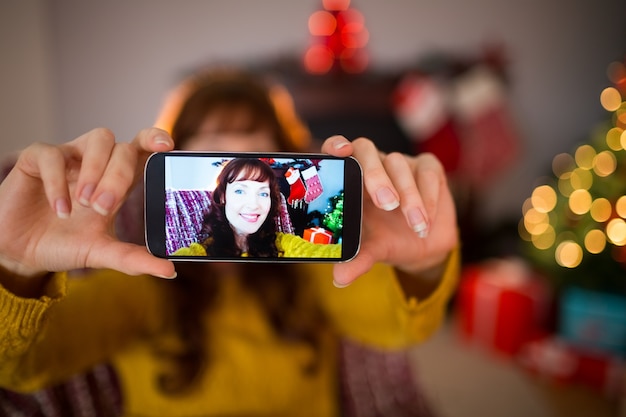 Redhead sorridente che prende un selfie a natale