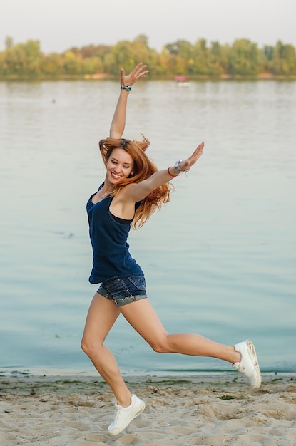 Donna rossa sorridente su una spiaggia vicino al grande fiume.