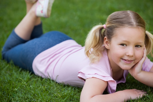 Smiling relaxed girl lying on grass at park