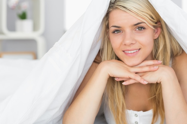 Smiling relaxed young woman lying in bed