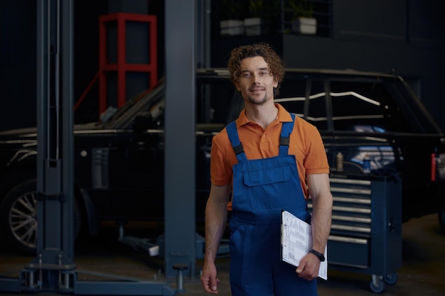 smiling repairman car technician walking with clipboard in hands
