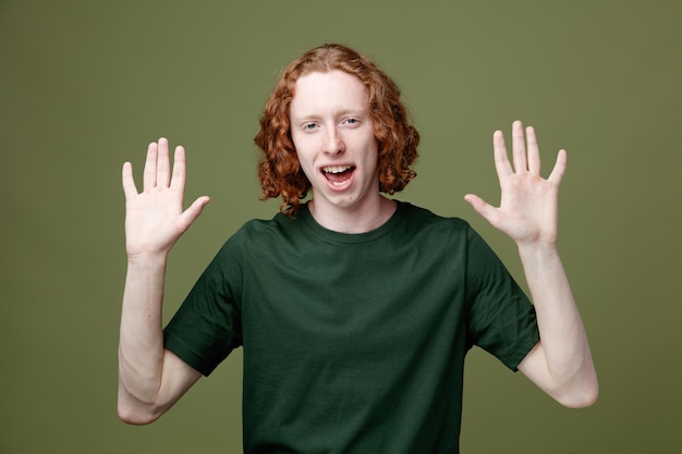 smiling rise up hands young handsome guy wearing green t shirt isolated on green background