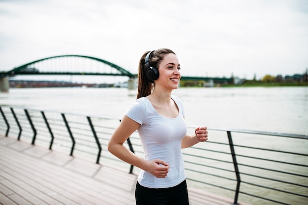 Smiling runner girl listening music.