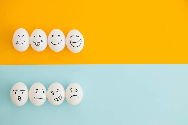 Smiling and sad eggs on a yellowblue background