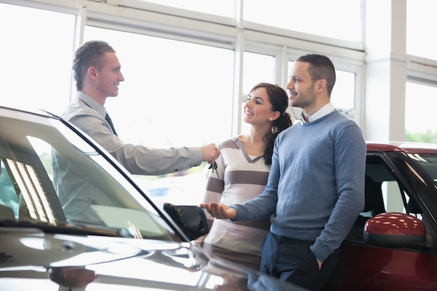 Smiling salesman handing keys to a couple