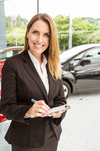 Smiling saleswoman checking a car