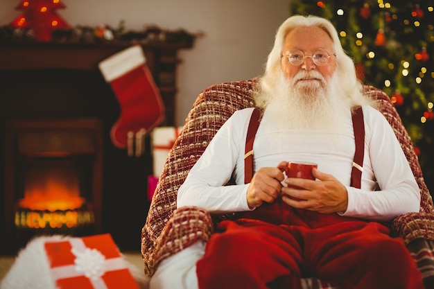 Smiling santa holding  cup of coffee