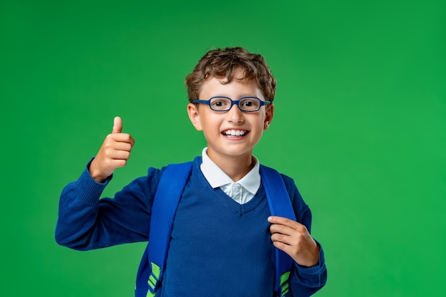 Scolaro sorridente in bicchieri, uniforme con uno zaino