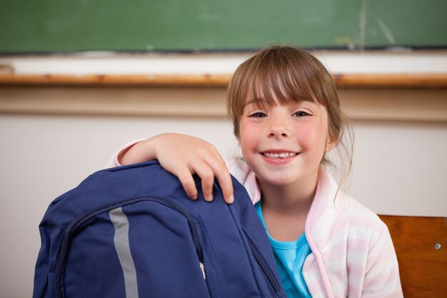 Scolara sorridente che posa con una borsa