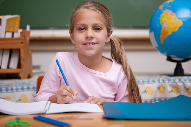 Smiling schoolgirl writing