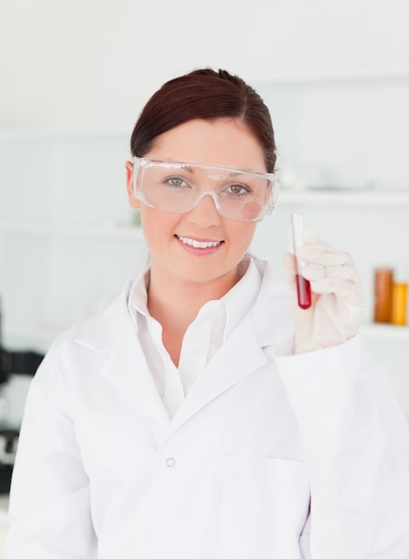 Smiling scientist looking at the camera while holding a  test tube