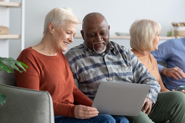 Smiling senior black man and caucasian woman using laptop