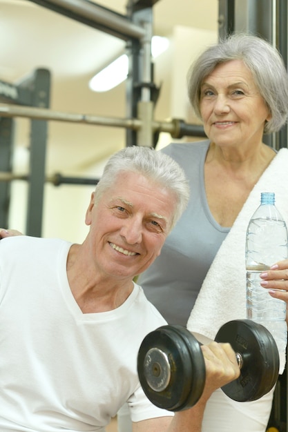 Foto sorridente coppia senior acqua potabile dopo l'esercizio in palestra