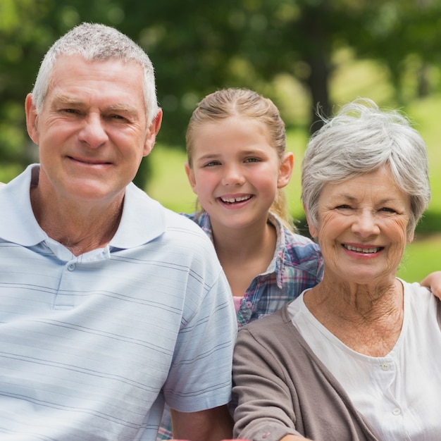 Smiling senior couple and granddaughter at park