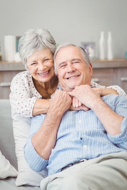 Smiling senior couple hugging while sitting on sofa