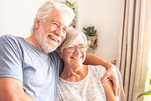 Foto una coppia anziana sorridente seduta a casa con le braccia attorno