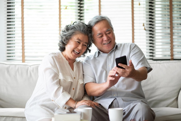 smiling senior couple taking selfie from phone while sitting at home