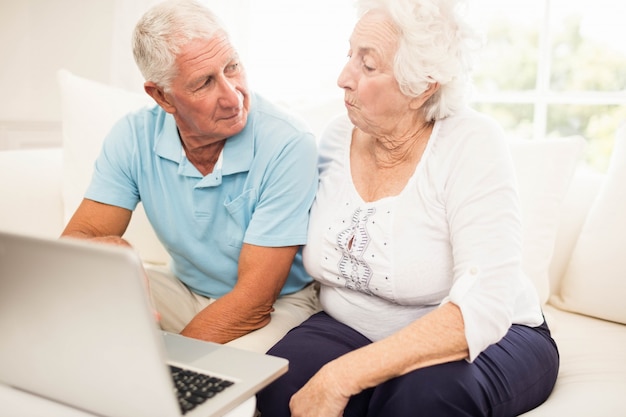 Smiling senior couple using laptop at home