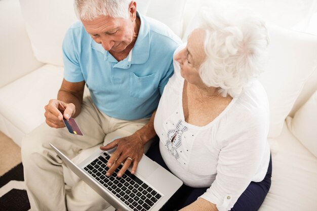 Smiling senior couple using laptop at home