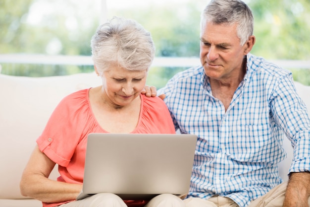 Smiling senior couple using laptop on the sofa