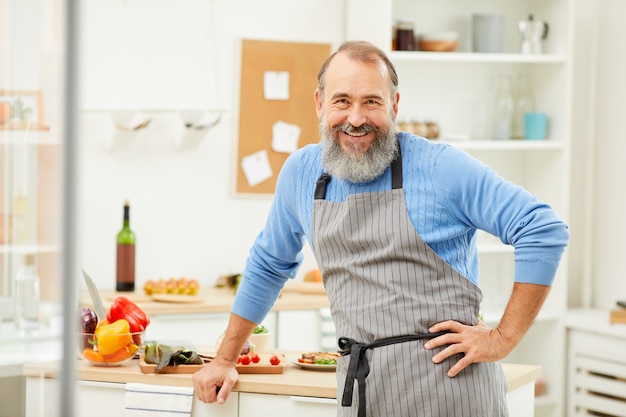 キッチンで料理をして笑顔の年配の男性