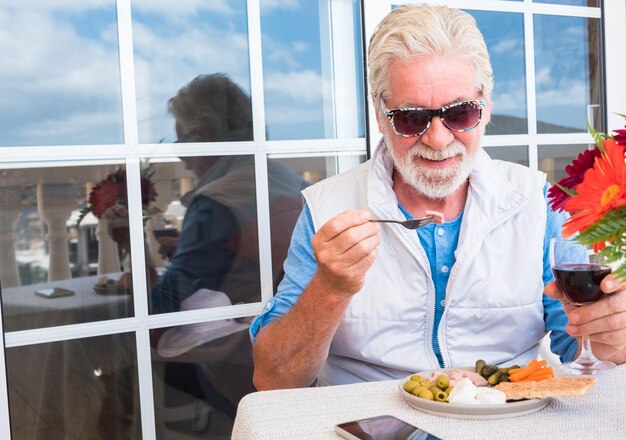 Foto uomo anziano sorridente che mangia il cibo sul tavolo